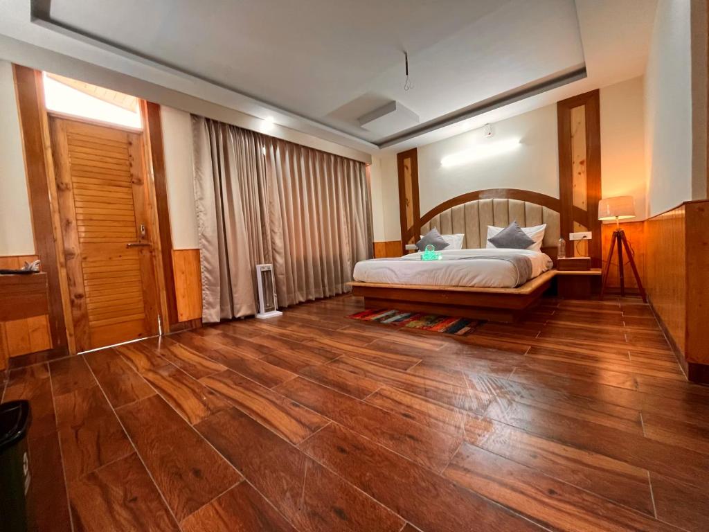 Schlafzimmer mit einem Bett und Holzboden in der Unterkunft Raghav Bro Stays in Junagadh