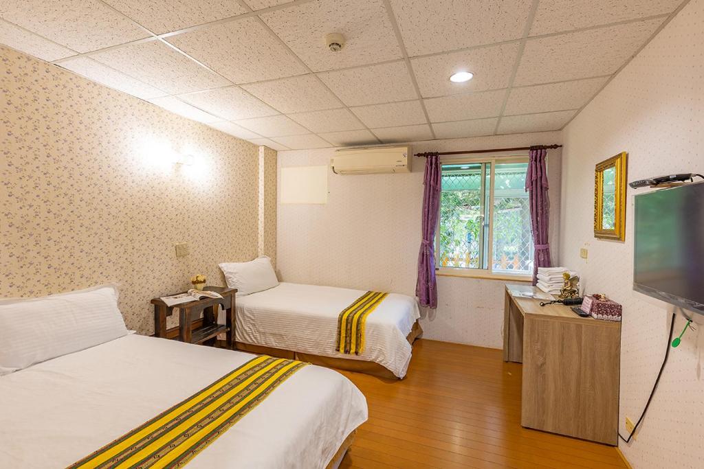 a room with two beds and a flat screen tv at Yishin Garden B&amp;B in Pinghe