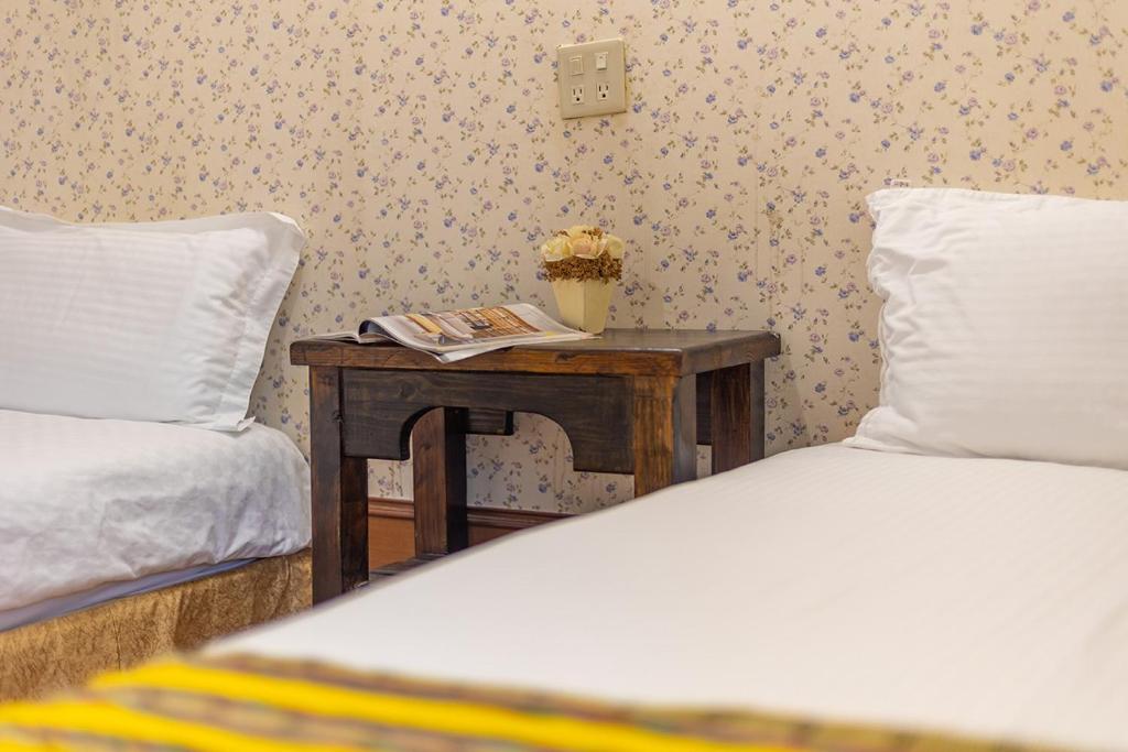 a bedroom with two beds and a table with a book at Yishin Garden B&amp;B in Pinghe