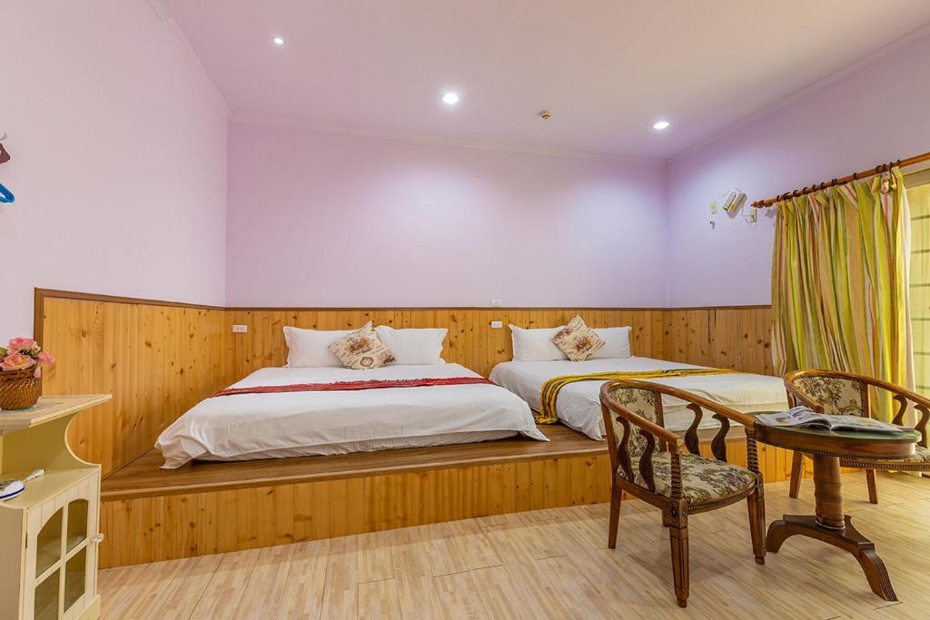 a bedroom with two beds and a desk and a table at Yishin Garden B&amp;B in Pinghe