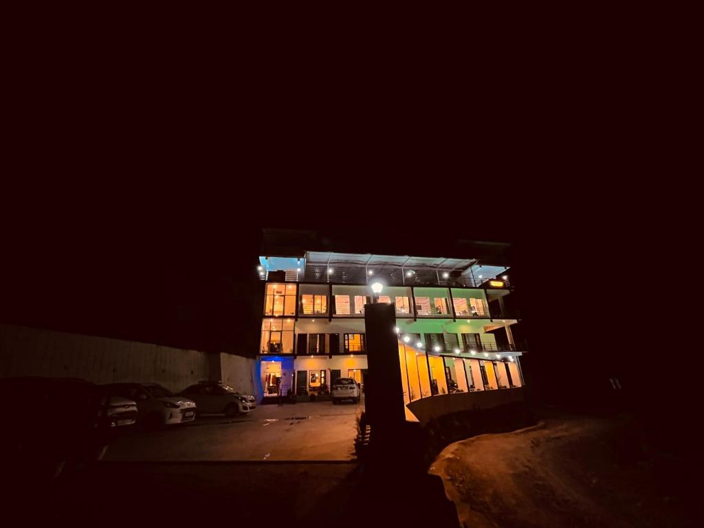 un edificio iluminado por la noche con un aparcamiento en Siluswar Hotel, en Junagadh