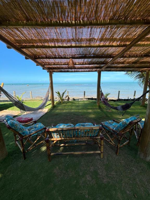 - deux hamacs et des chaises sous un toit sur la plage dans l'établissement Pousada Casarão - Pé na Areia Cumuruxatiba, à Cumuruxatiba