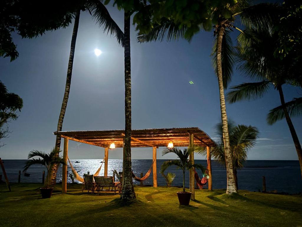 a gazebo on the beach at night with palm trees at Pousada Casarão - Pé na Areia Cumuruxatiba in Cumuruxatiba