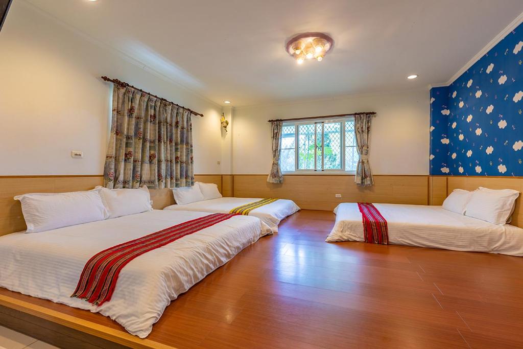 two beds in a room with wood floors and a window at Yishin Garden B&amp;B in Pinghe