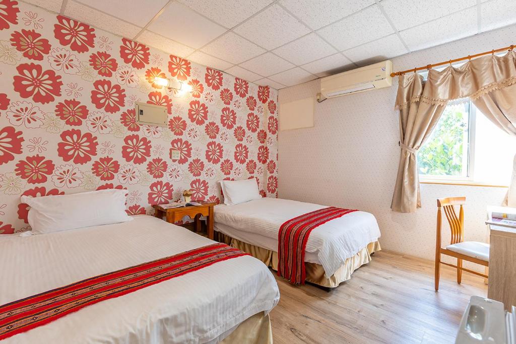 two beds in a room with red and white wallpaper at Yishin Garden B&amp;B in Pinghe