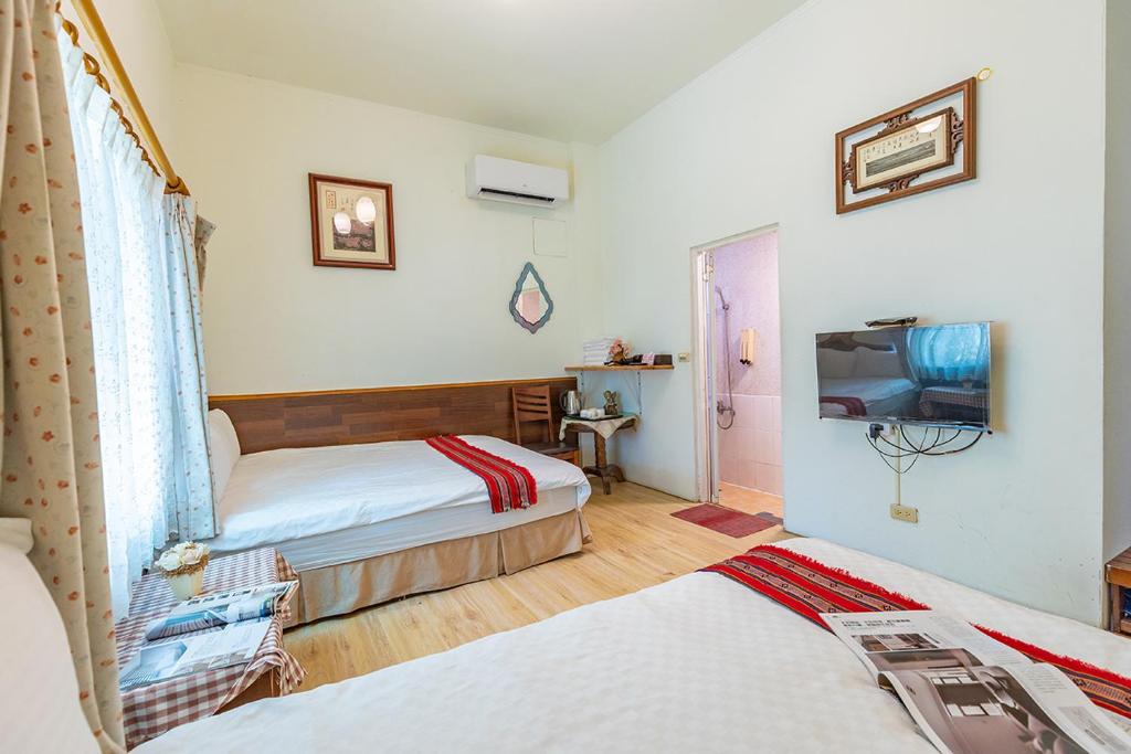 a hotel room with two beds and a television at Yishin Garden B&amp;B in Pinghe