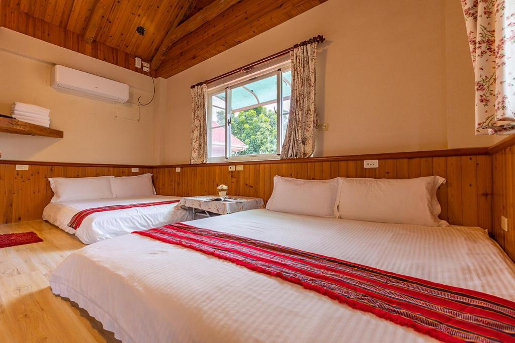 two beds in a room with a window at Yishin Garden B&amp;B in Pinghe