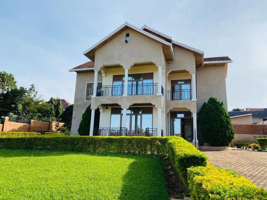 a large house with a hedge in front of it at Quiet and Spacious Hidden Gem in Kigali with Breathtaking Views right by the Airport in Kigali