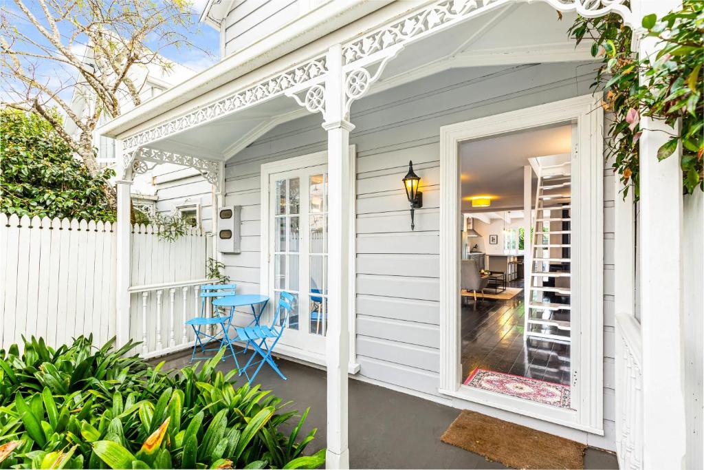 a white house with a porch with a blue chair at Beautiful Ponsonby Villa by Zodiak Stays in Auckland
