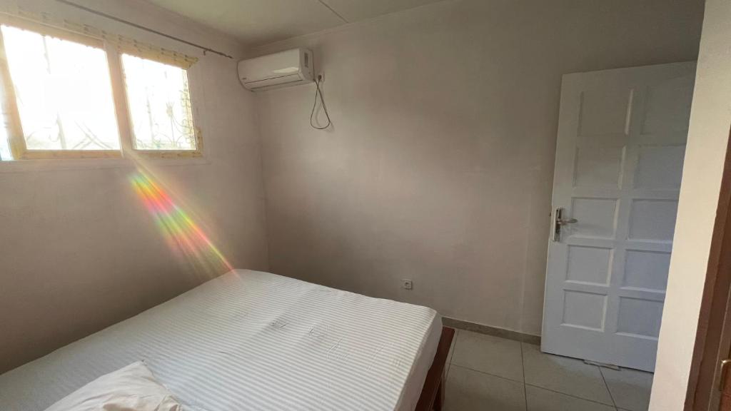 a bed with a rainbow in a room with a window at Studio ovangi bis in Libreville