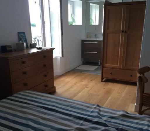 a bedroom with a bed and a dresser and a bathroom at Familly Home in Grandcamp-Maisy