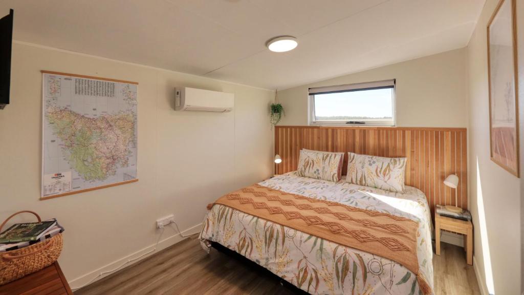 ein Schlafzimmer mit einem Bett und einer Karte an der Wand in der Unterkunft Badger's View Farmstay Cottage in Railton