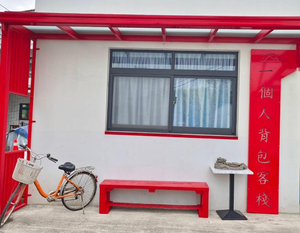 a bike parked next to a building with a red bench at 一個人背包客棧 in Wujie