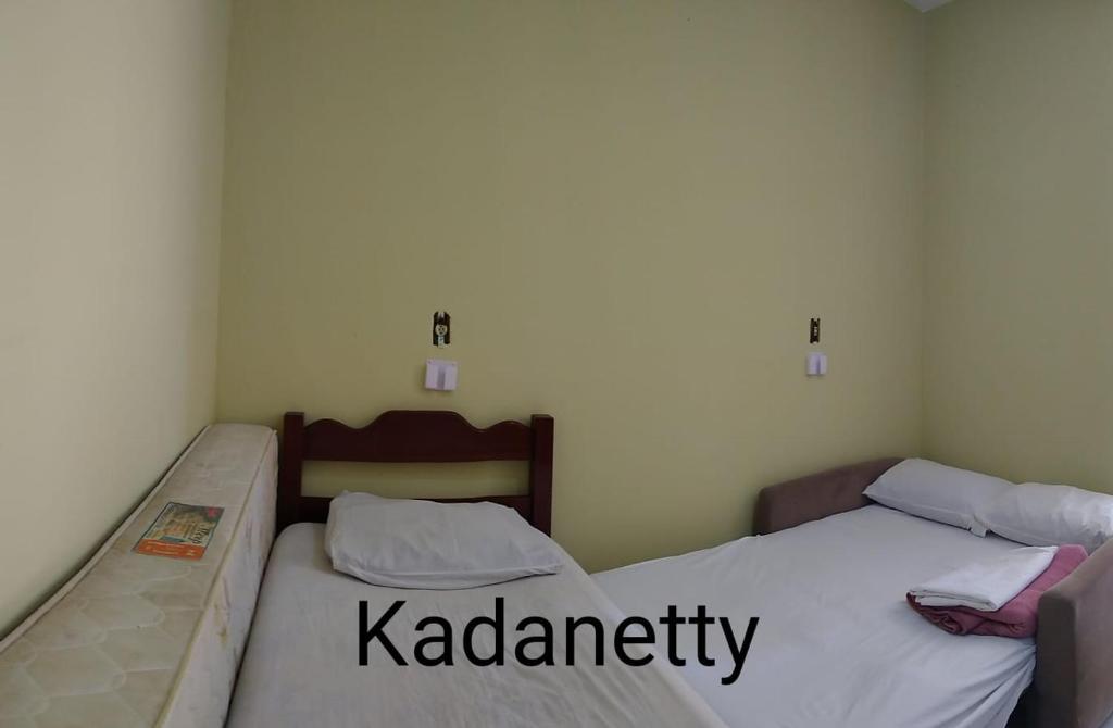 2 camas en una habitación pequeña con las palabras kacienna en Condomínio Santa Rosa, en Caraguatatuba