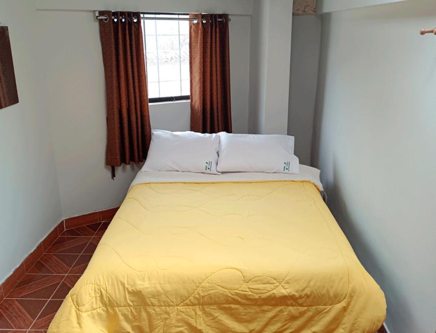 ein gelbes Bett in einem Zimmer mit Fenster in der Unterkunft Oro Verde Hostal in Cusco