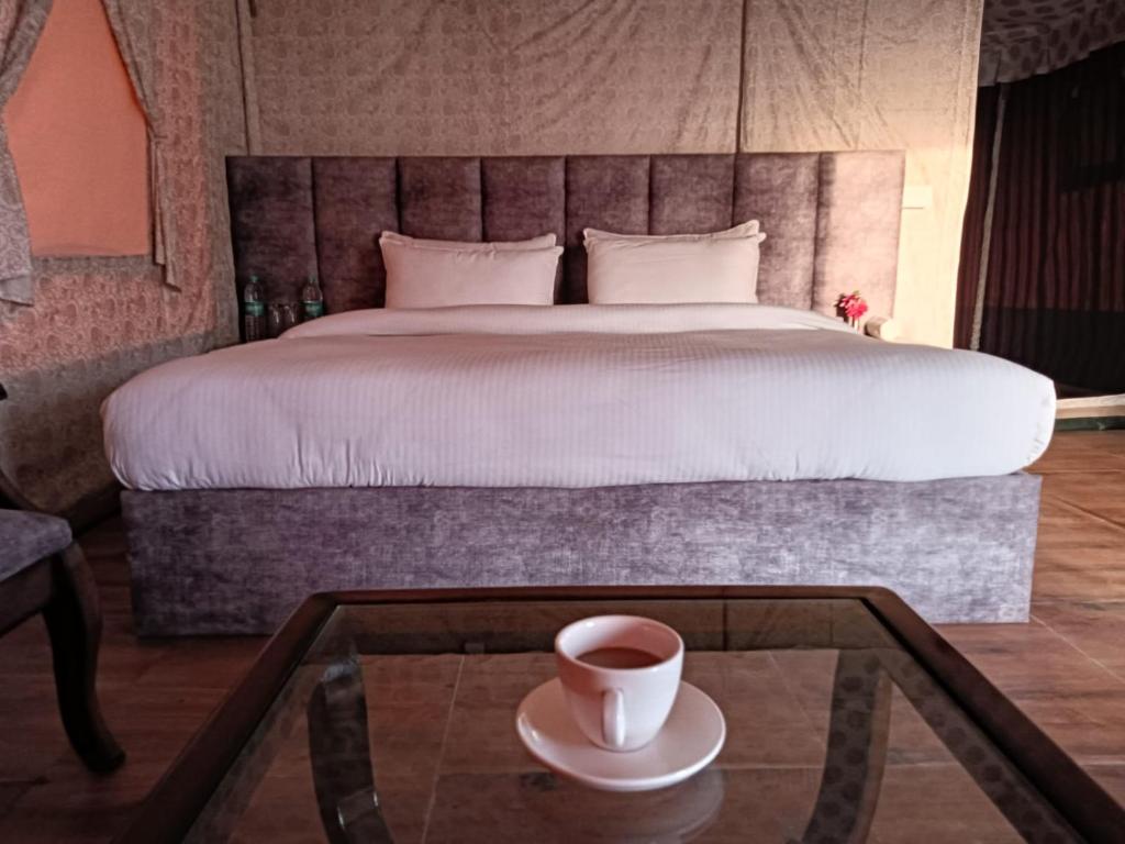 Schlafzimmer mit einem Bett und einer Tasse Kaffee auf einem Tisch in der Unterkunft Pulastya Wellness Resort in Saharanpur