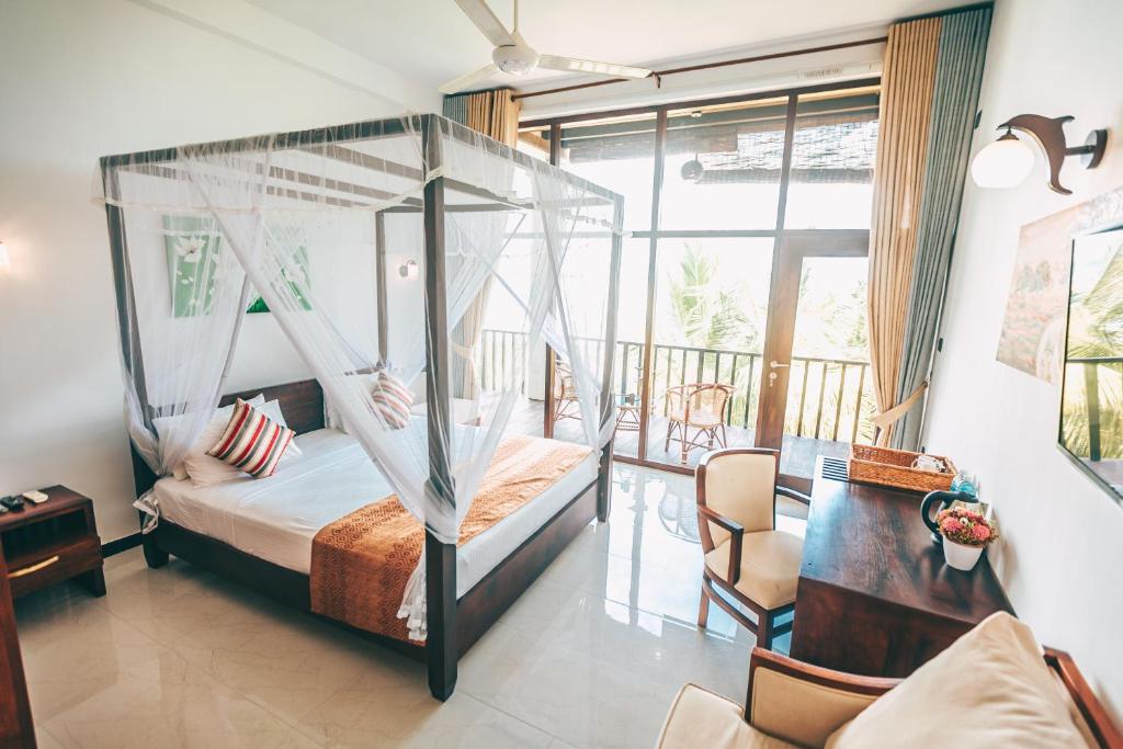 una camera da letto con letto a baldacchino e balcone di Samudra Beach Resort a Tangalle