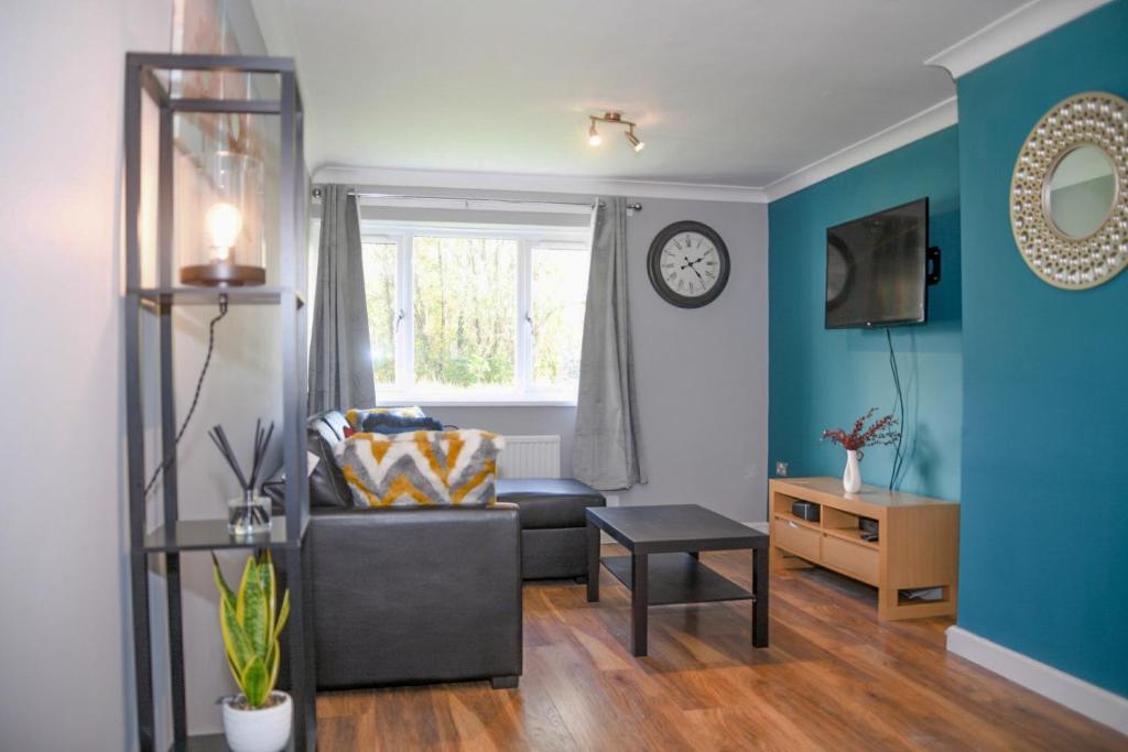 sala de estar con sofá y reloj en la pared en 2ndHomeStays- Willenhall-A Serene 3 Bed House with a Garden View-Suitable for Contractors and Families-Sleeps 9 - 7 mins to J10 M6 and 21 mins to Birmingham en Willenhall