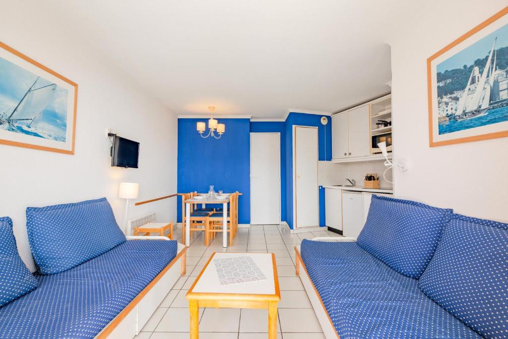 un salon avec deux canapés bleus et une table dans l'établissement Résidence le Hameau de Cap Esterel - maeva Home - Appartement 2 Pièces 5 Personnes - Confort MAE-1127, à Saint-Raphaël