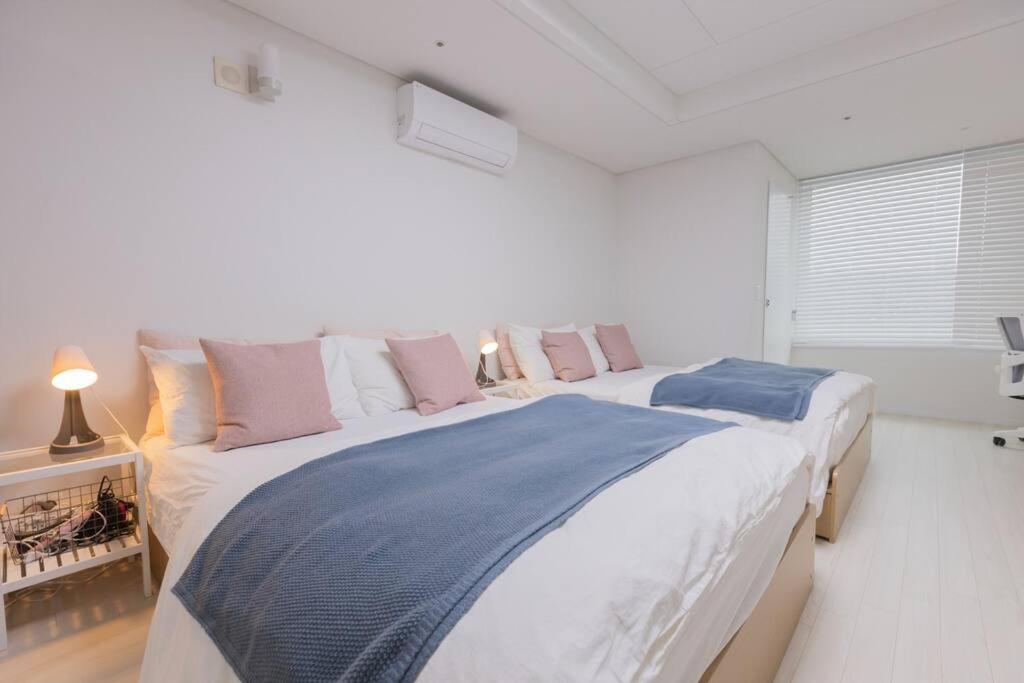 a white bedroom with a large bed with pillows at Mirae stay 67 in Seoul