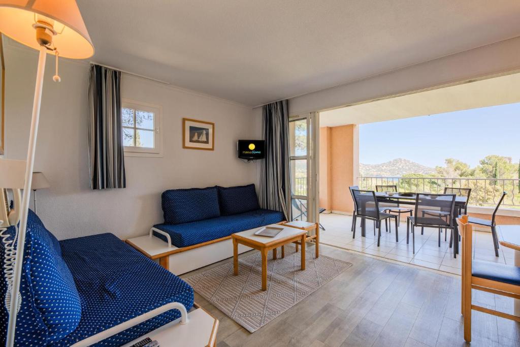 un salon avec un canapé bleu, une table et des chaises dans l'établissement Résidence le Hameau de Cap Esterel - maeva Home - Appartement 2 Pièces 7 Personnes - Sélection MAE-1473, à Saint-Raphaël