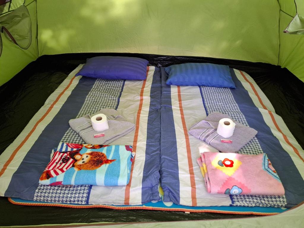 Una cama con toallas y aseos encima. en Two Rocks Bungalows, en Baan Tai