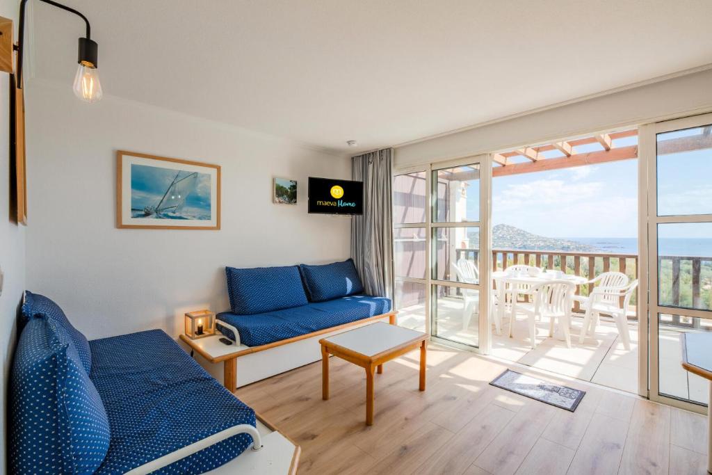 uma sala de estar com um sofá azul e uma varanda em Résidence le Hameau de Cap Esterel - maeva Home - Appartement 2 Pièces 7 Pe 11 em Saint-Raphaël