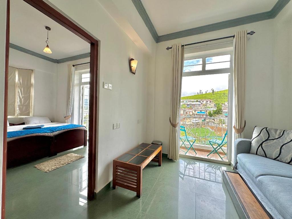 een slaapkamer met een bed, een bank en een raam bij Royal Pearl Hills (Pvt) Ltd. in Nuwara Eliya