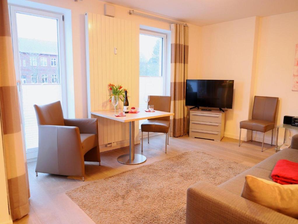 salon ze stołem i telewizorem w obiekcie Miit Liebe zum Detail eingerichtete 2-Zimmer-Ferienwohnung im Zentraum von Westerland w mieście Westerland