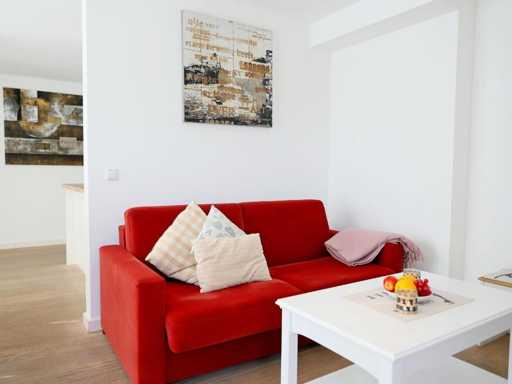 ein rotes Sofa im Wohnzimmer mit einem weißen Tisch in der Unterkunft Ferienhaus mit neuen und sehr hochwertigen Appartements in zentraler Lage in Westerland in Westerland