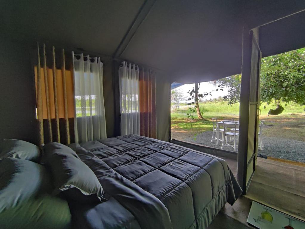 1 dormitorio con cama grande y ventana grande en Harmony Haven Eco Camp, Udawalawa, en Udawalawe