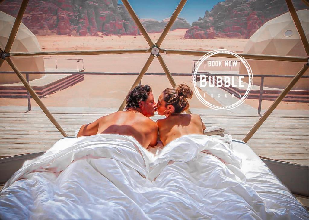 um homem e uma mulher deitados na cama em Wadi rum Bubble luxury camp em Wadi Rum