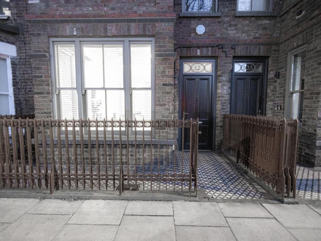 a fence in front of a brick building with two doors at Modern Deluxe Five Bedroom House near Chalk Farm Station by Belvilla in London