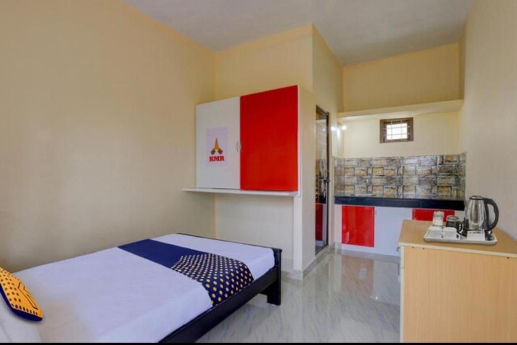 a bedroom with a bed and a kitchen with red cabinets at Kochu Mariya Residency in Punalūr