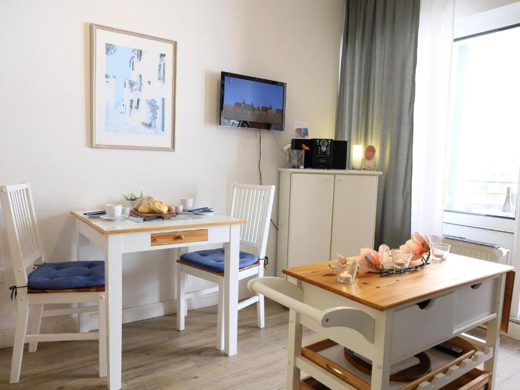 sala de estar con mesa, sillas y TV en Appartement mit 2 Balkonen, en Westerland
