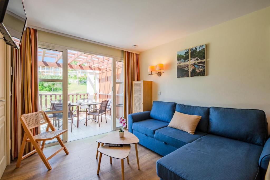 un salon avec un canapé bleu et une table dans l'établissement Résidence le Village de Cap Esterel - maeva Home - Appartement 2 Pièces 6 Personnes - Sélection MAE-8258, à Saint-Raphaël