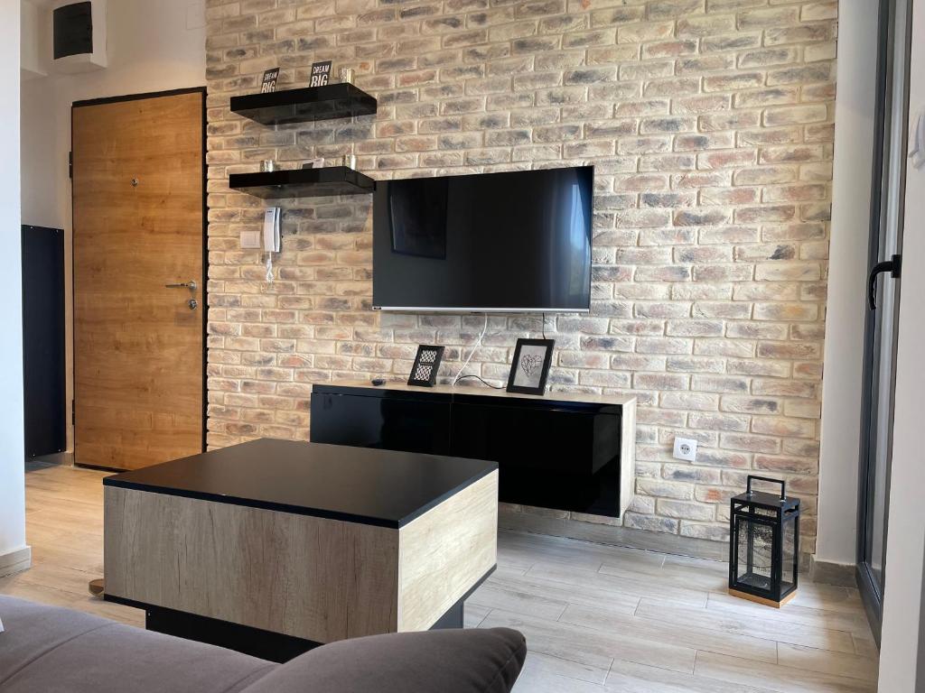 uma sala de estar com uma parede de tijolos e uma televisão de ecrã plano em Divcibarski cardak em Divčibare