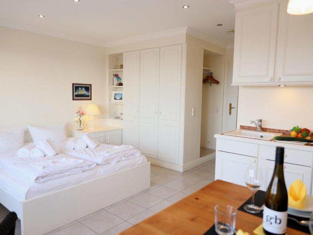 um quarto branco com uma cama e uma cozinha em Wohnen Sie im Herzen Westerlands, in einer komplett neu renovierten 1-Zimmer Wohnung em Westerland