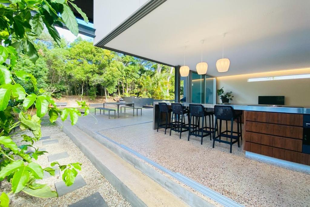 an outdoor kitchen and dining area of a house with trees at Dune Ten by Kingscliff Accommodation in Fingal Head