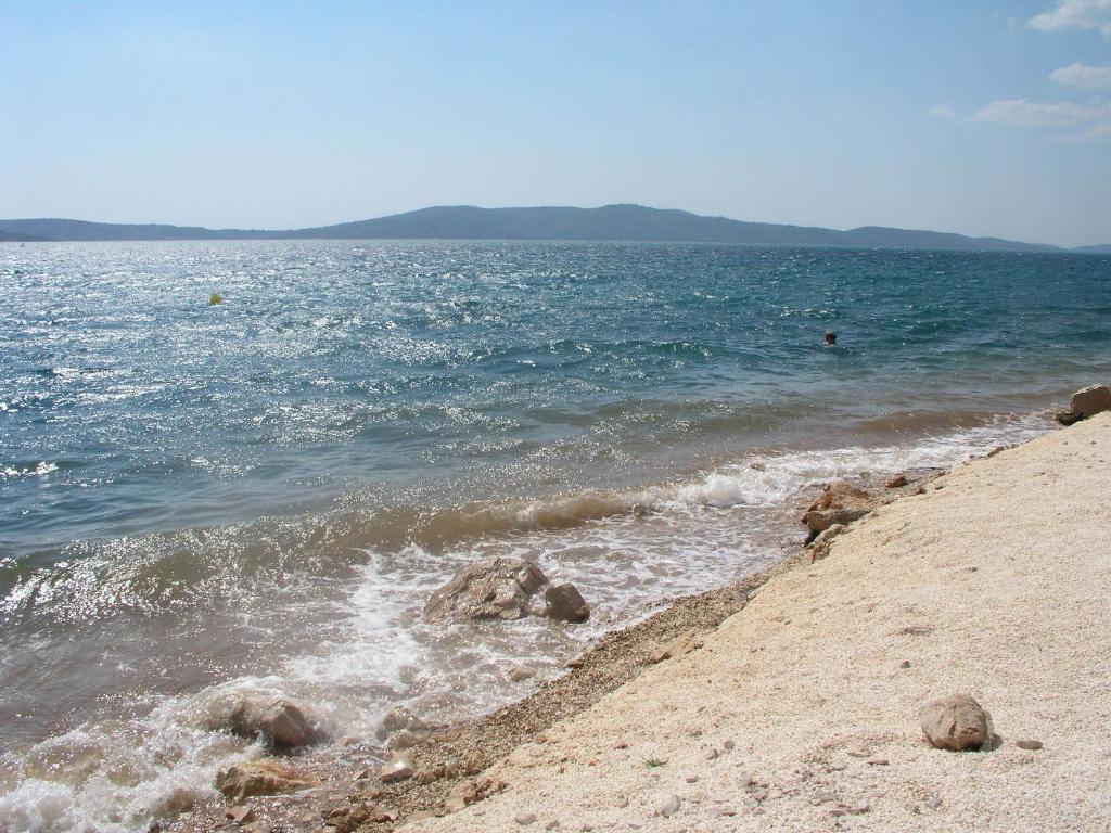 a beach with rocks and the ocean on a sunny day at Apartments Jakobina in Brodarica