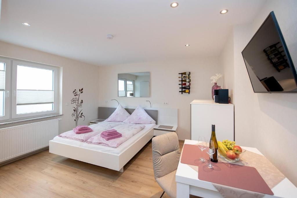 a white bedroom with a bed and a table at Studio Apartment am historischen Matthiasturm in Neef