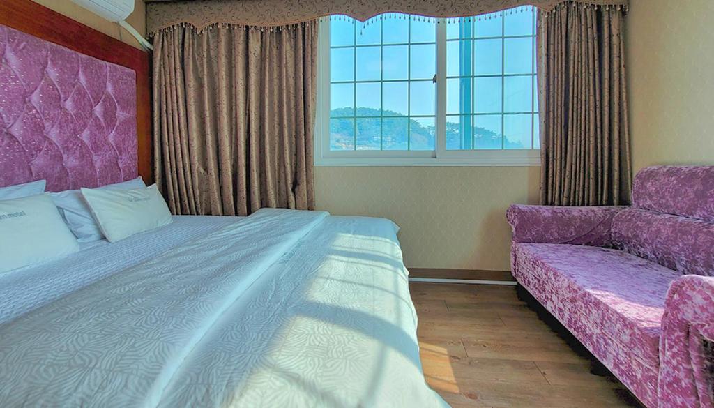 a bedroom with a bed and a couch and a window at Queen motel in Tongyeong