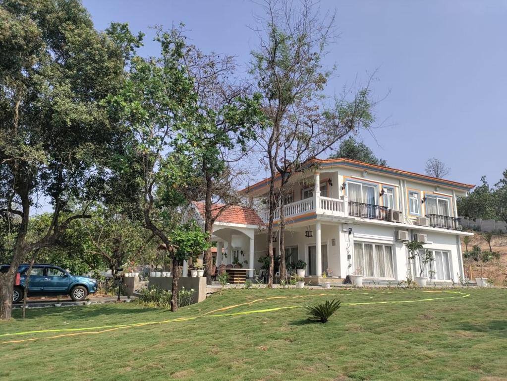 een groot wit huis met een auto ervoor geparkeerd bij Dezire Holidays South Goa in Goa