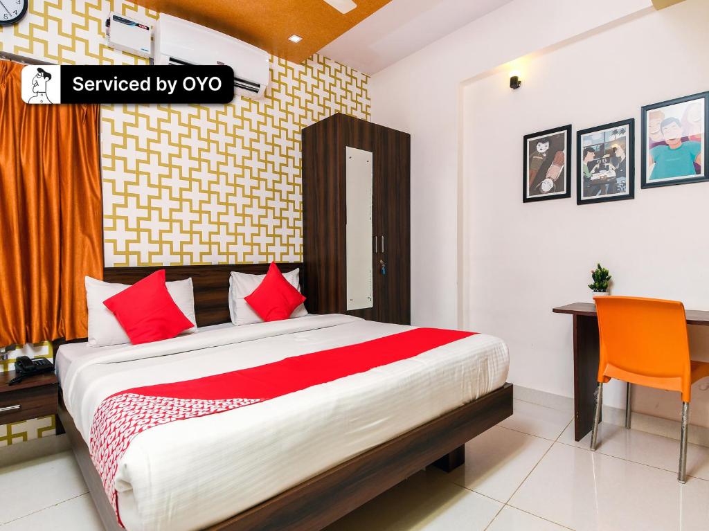 Yelahanka的住宿－Super Collection O Bangalore Airport Road，一间卧室配有一张带红色枕头的床和一张书桌