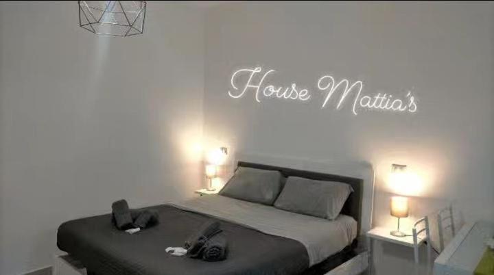 - une chambre avec un lit avec deux lumières et un panneau indiquant des martinis maison dans l'établissement House Mattia, à Bari