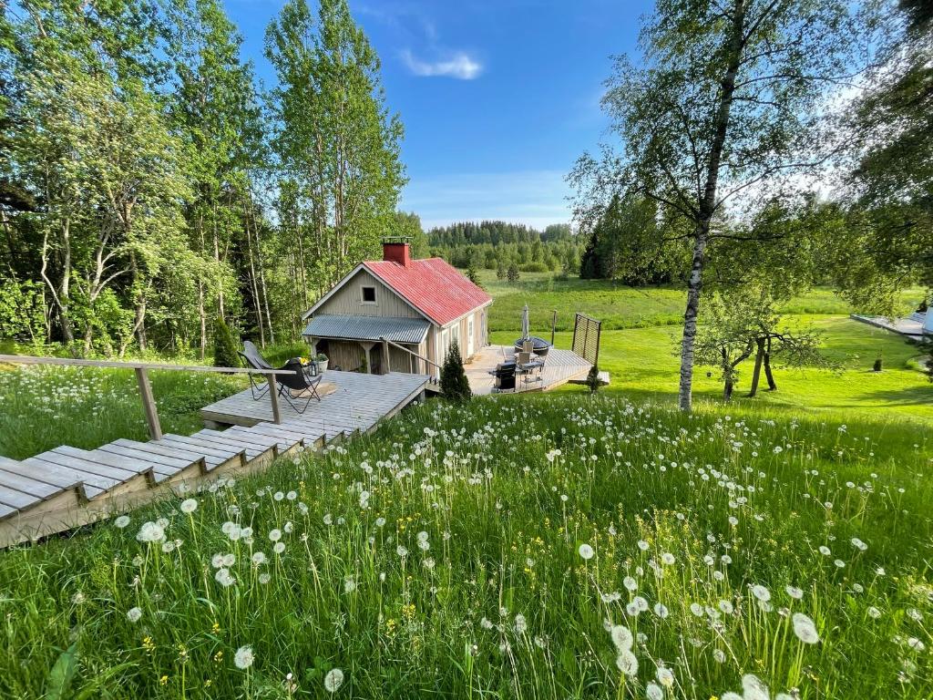 a house with a deck in a field with flowers at Romantic cottage with sauna in Porvoo