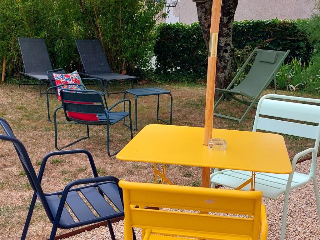 um grupo de cadeiras e uma mesa com um guarda-chuva em L'authentik petit hôtel Le Refuge de Mamie Yo 