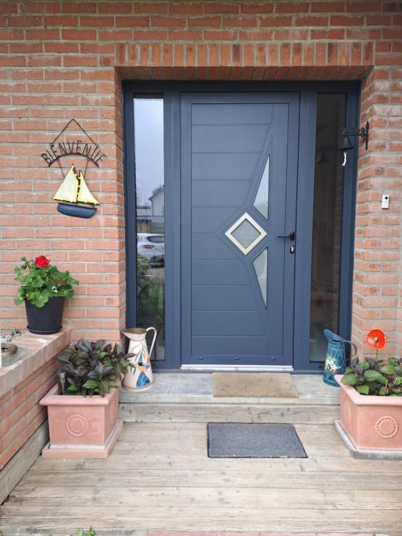 a blue front door of a brick house with potted plants at Les grandes Masures B&B in Varengeville-sur-Mer