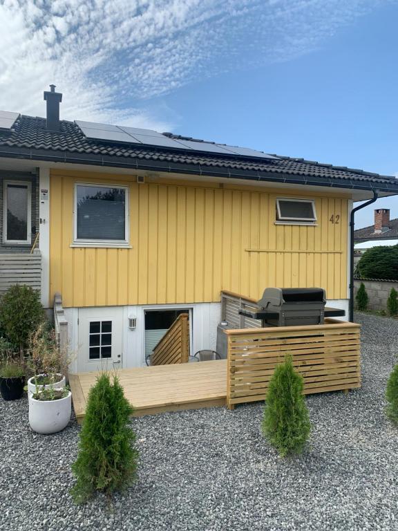 una casa gialla con terrazza e griglia di Apartment with access to pool and sauna a Porsgrunn