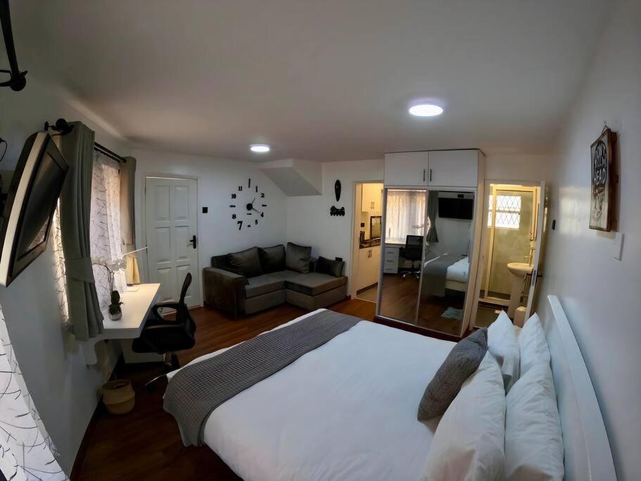 sypialnia z dużym białym łóżkiem i kanapą w obiekcie Cozy Corner Chic Studio Haven w mieście Nairobi